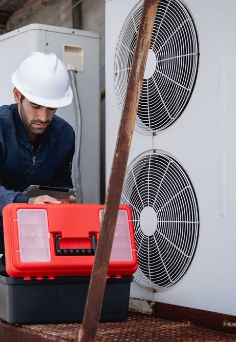 HVAC technician with a red toolbox inspecting an outdoor multi-fan system