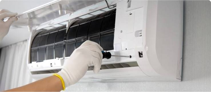 Gloved technician servicing a wall-mounted air conditioner