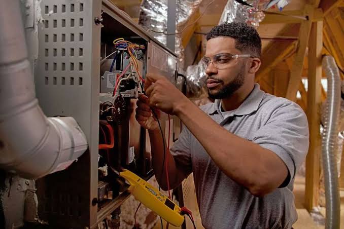 Technician checking wiring inside a residential heating system